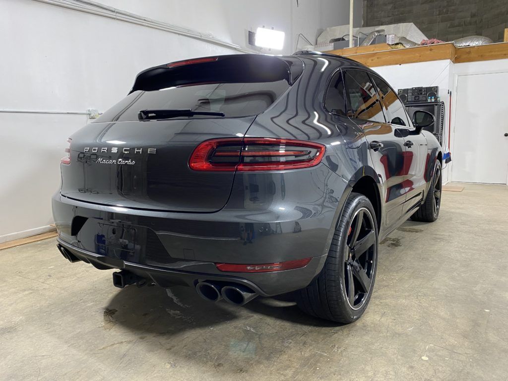 A gray porsche macan is parked in a garage.
