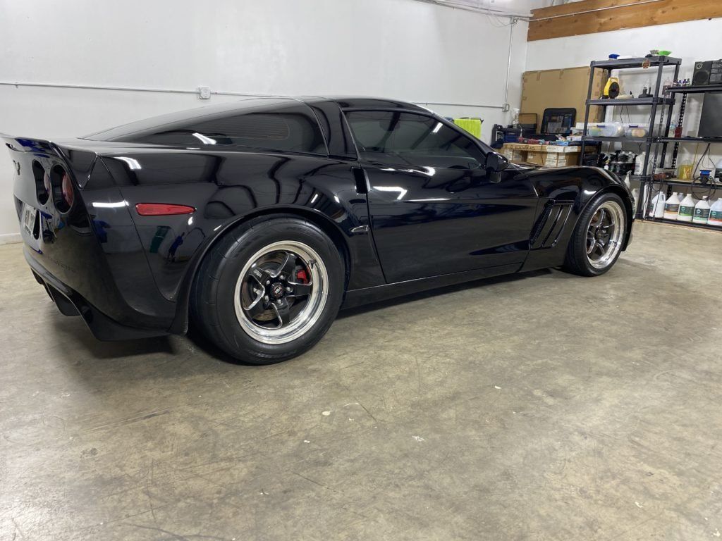 A black sports car is parked in a garage.