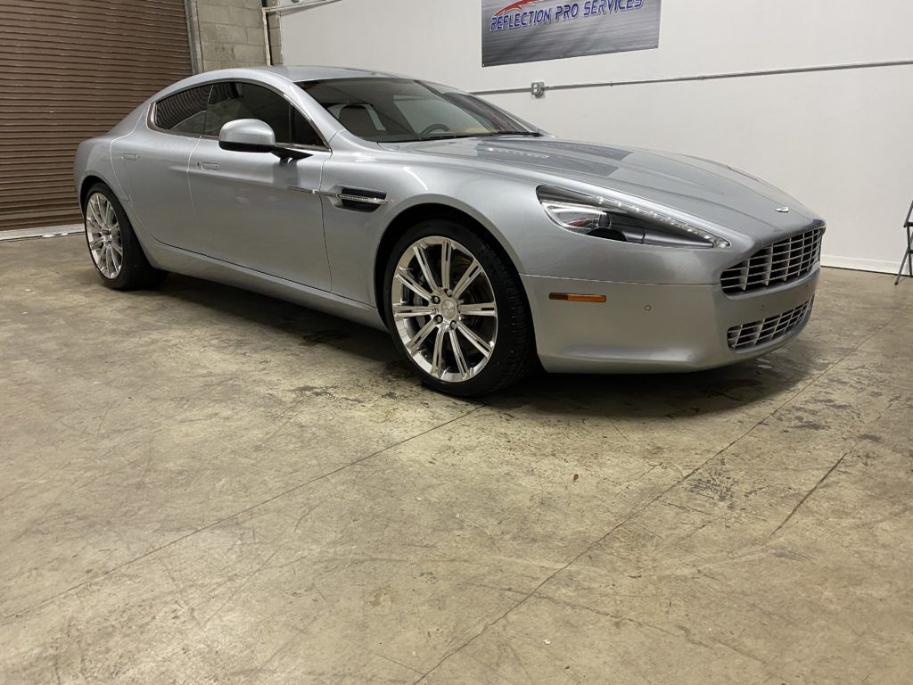 A silver aston martin sports car is parked in a garage.