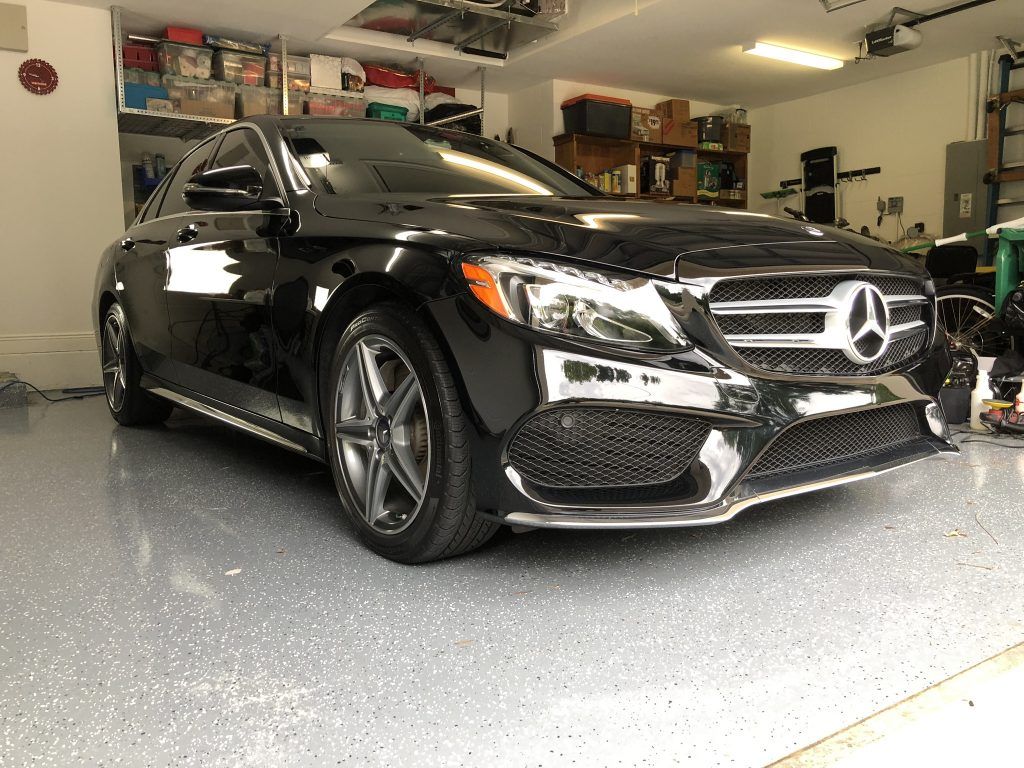 A black mercedes benz is parked in a garage.