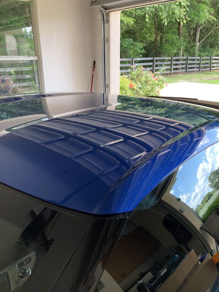 A blue car is parked in a garage with the roof open