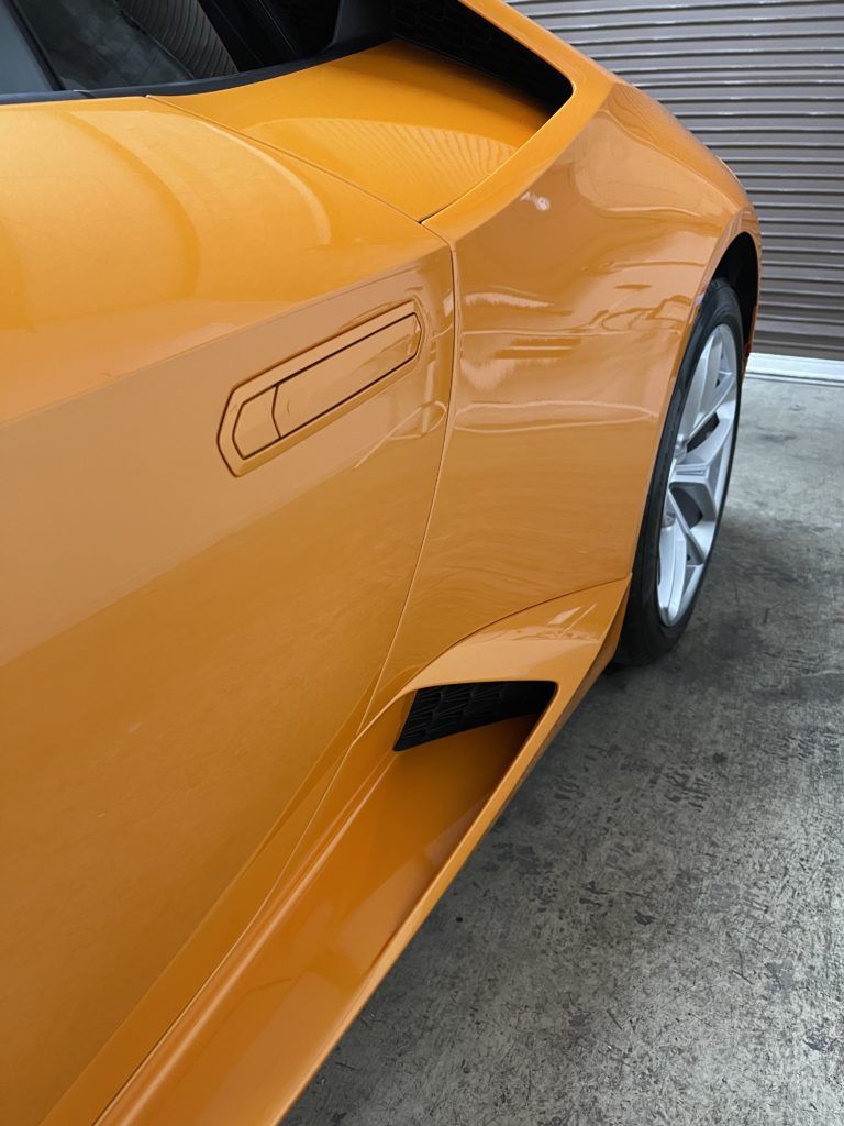 A close up of a yellow sports car parked in a parking lot.