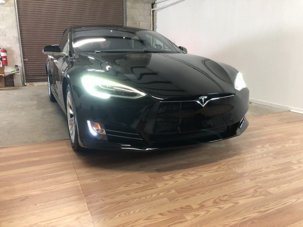 A black tesla model s is parked in a garage.
