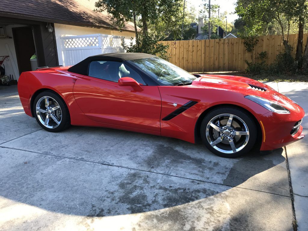 A red corvette convertible is parked in a driveway.