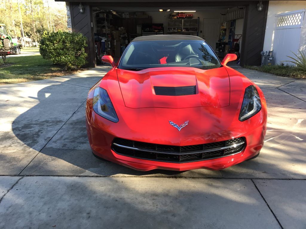 A red sports car is parked in a driveway in front of a garage.