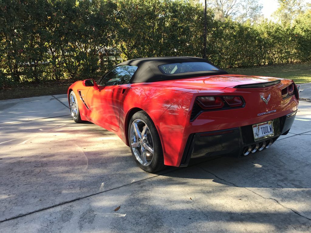 A red corvette convertible is parked in a driveway.