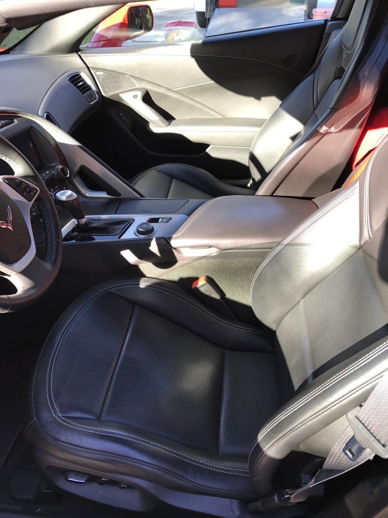 The interior of a sports car with black leather seats and a steering wheel.