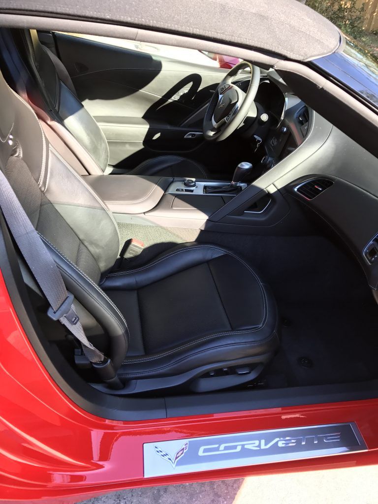 The inside of a red corvette with the door open.