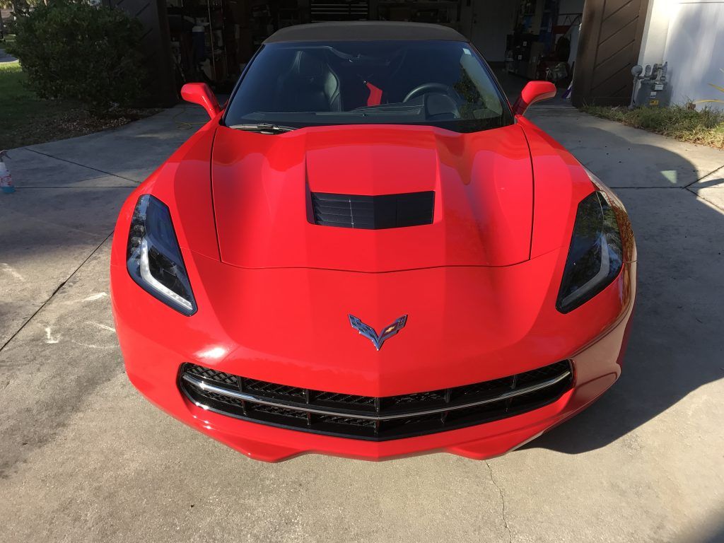 A red corvette is parked in a driveway.