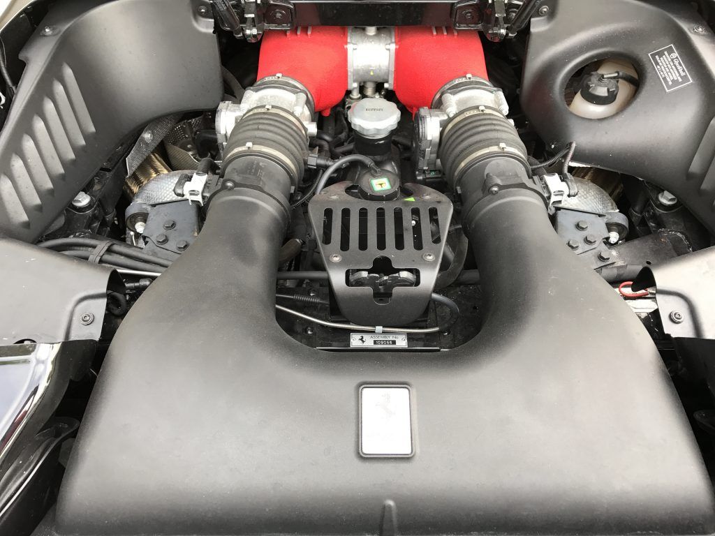 A close up of the engine of a car with a red hood.