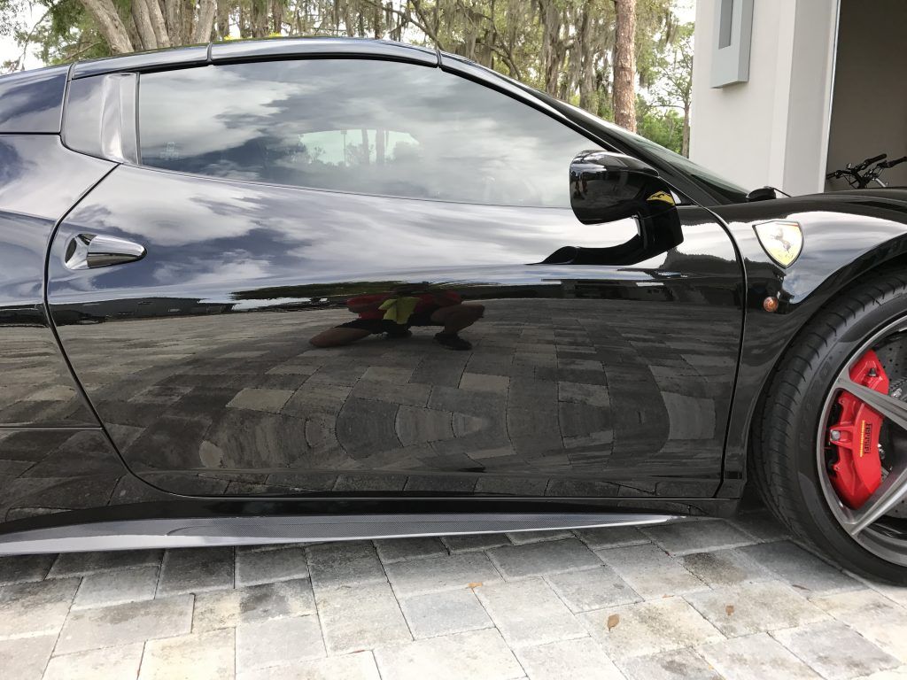 A black sports car is parked in a driveway next to a garage.