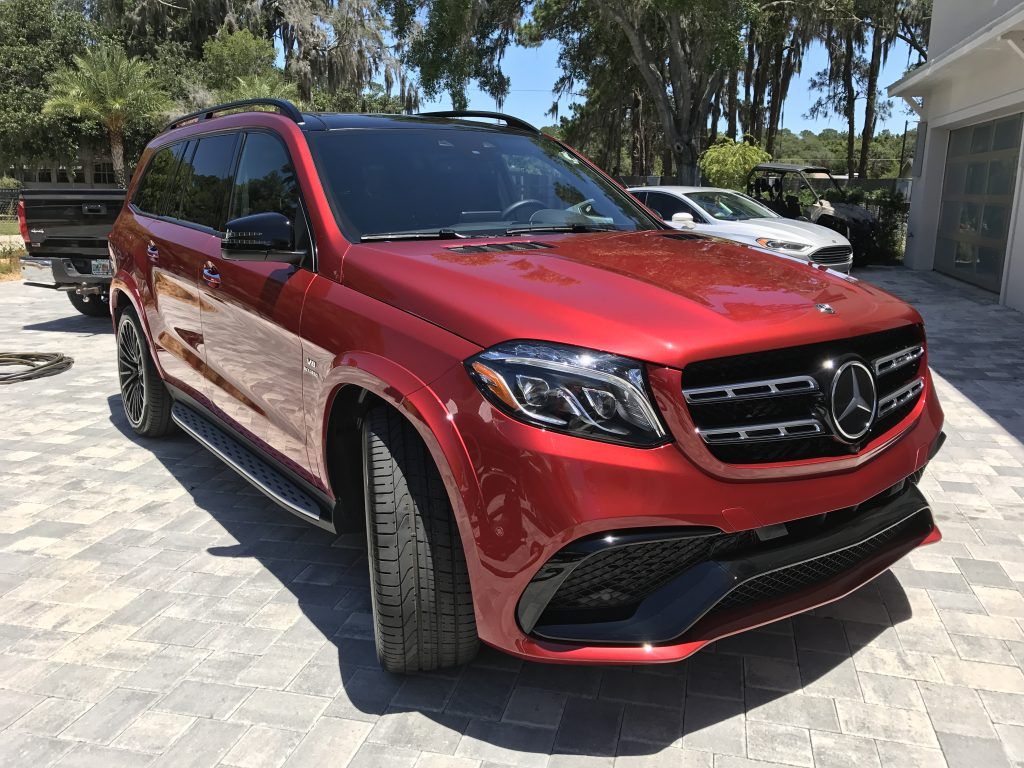 A red mercedes benz gls 63 amg is parked in a driveway.
