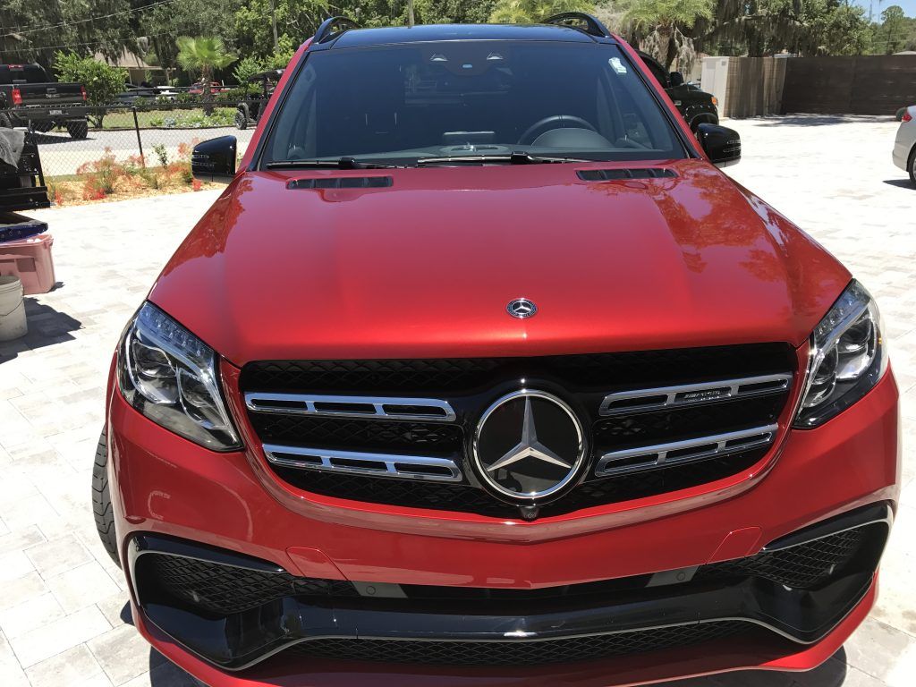 A red mercedes benz suv is parked in a driveway.