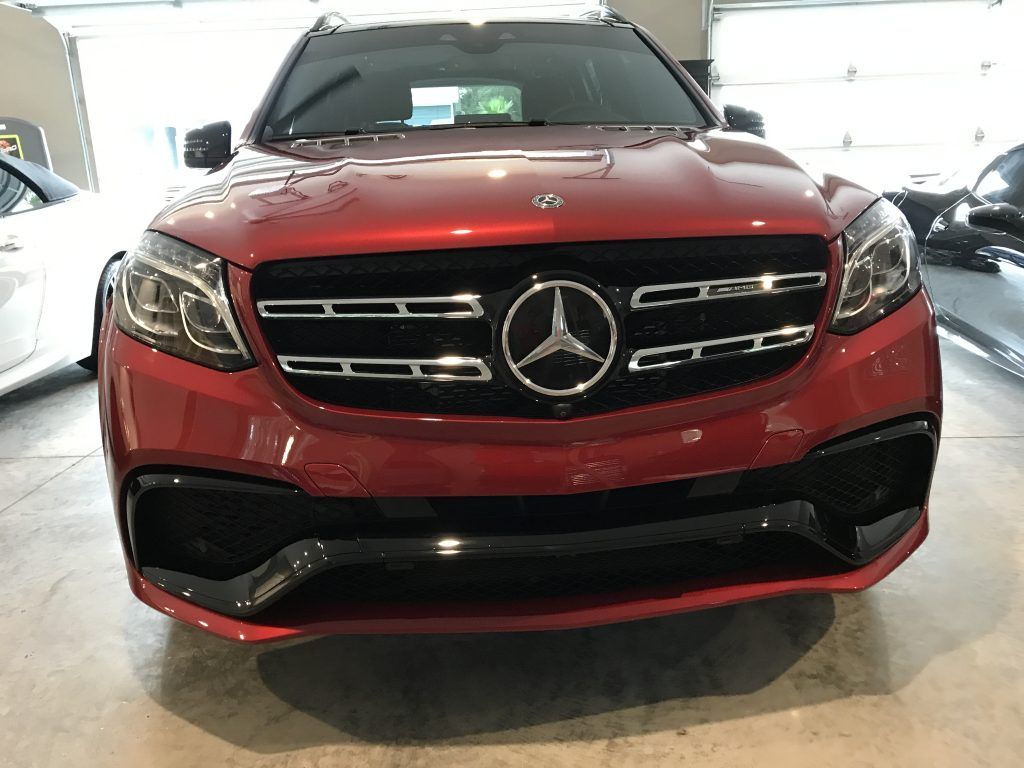 A red mercedes benz gl63 amg is parked in a garage.
