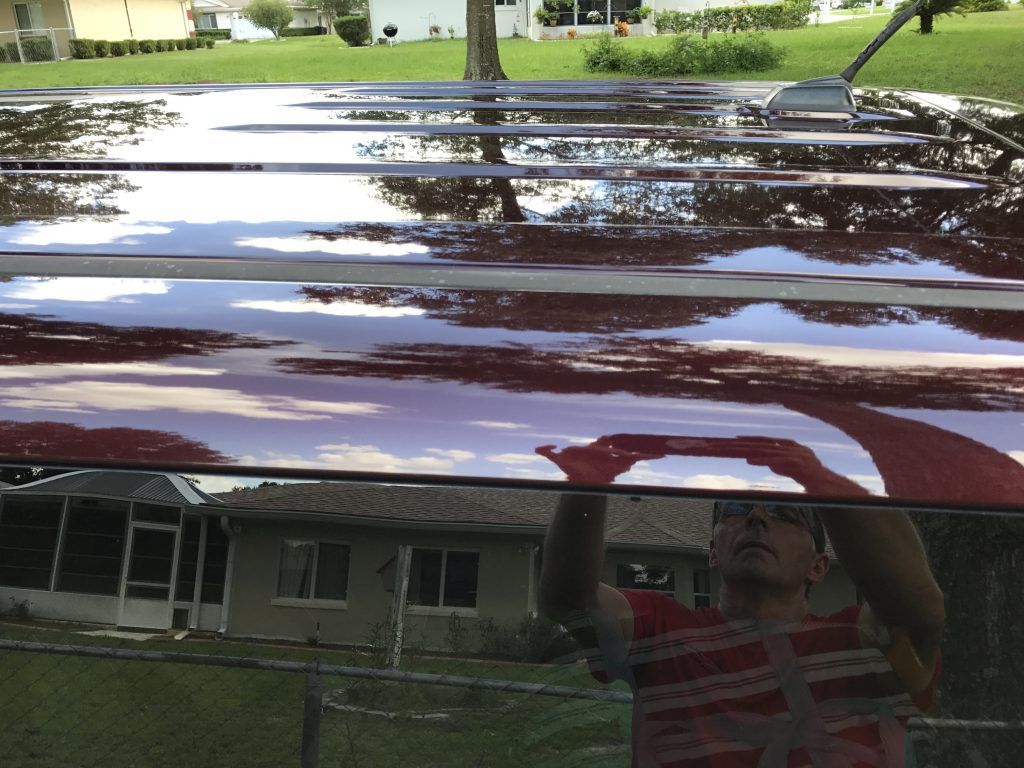 A person is standing in front of a red car
