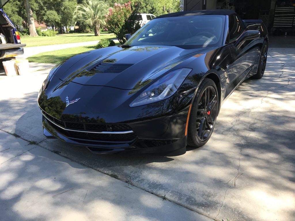 A black sports car is parked in a driveway.