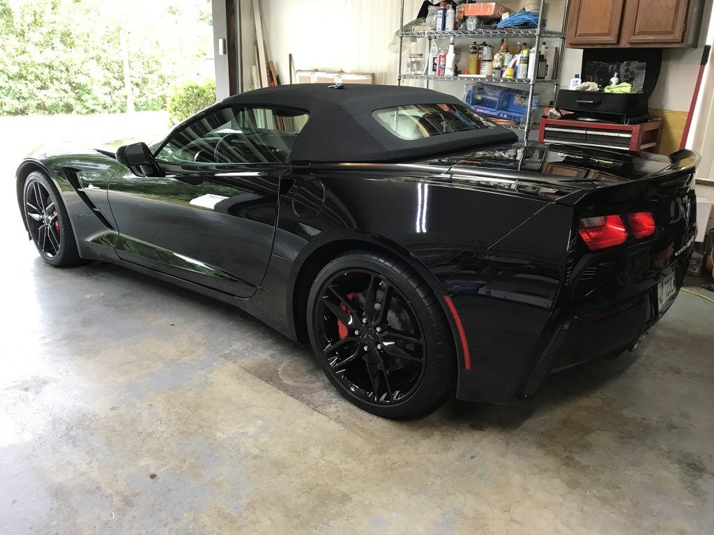 A black corvette convertible is parked in a garage.