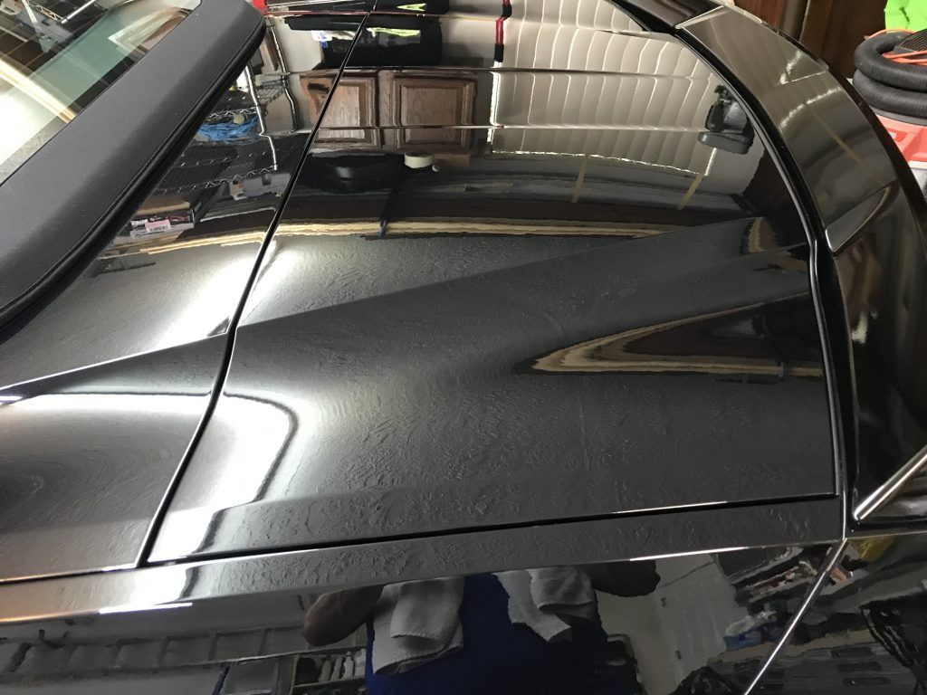A close up of a car 's hood in a garage.