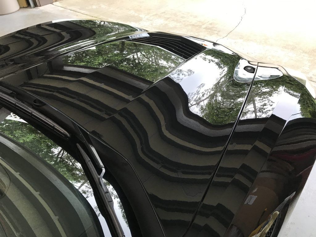 The hood of a black car is reflected in the windshield.