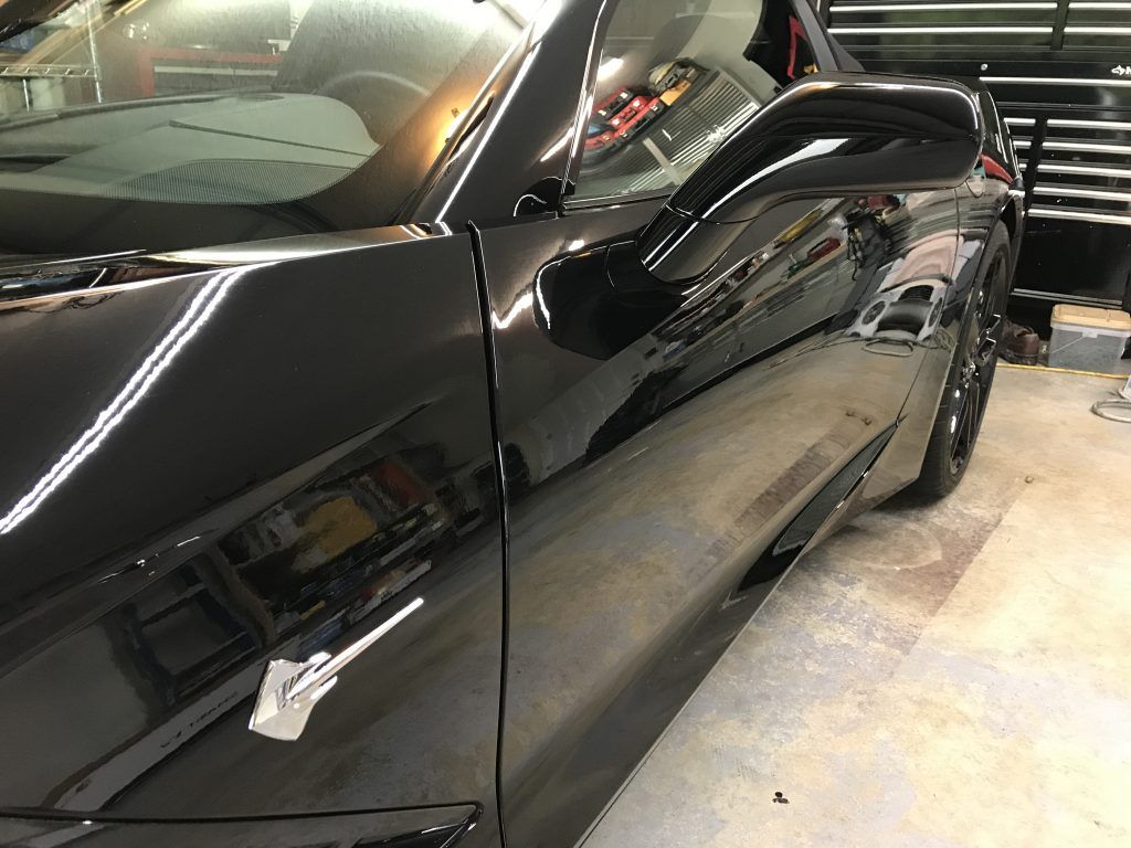 A black sports car is parked in a garage.