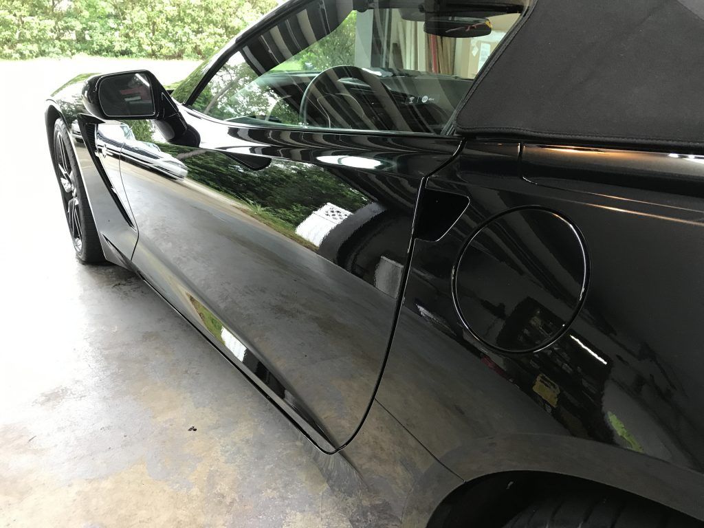 A black sports car is parked in a garage.