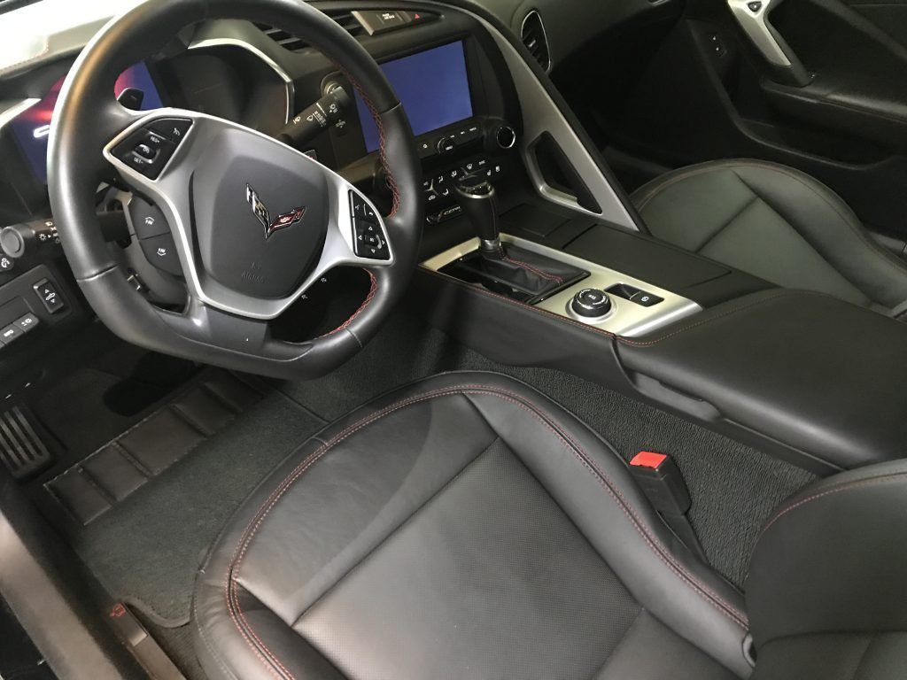 The interior of a corvette with black leather seats and a steering wheel