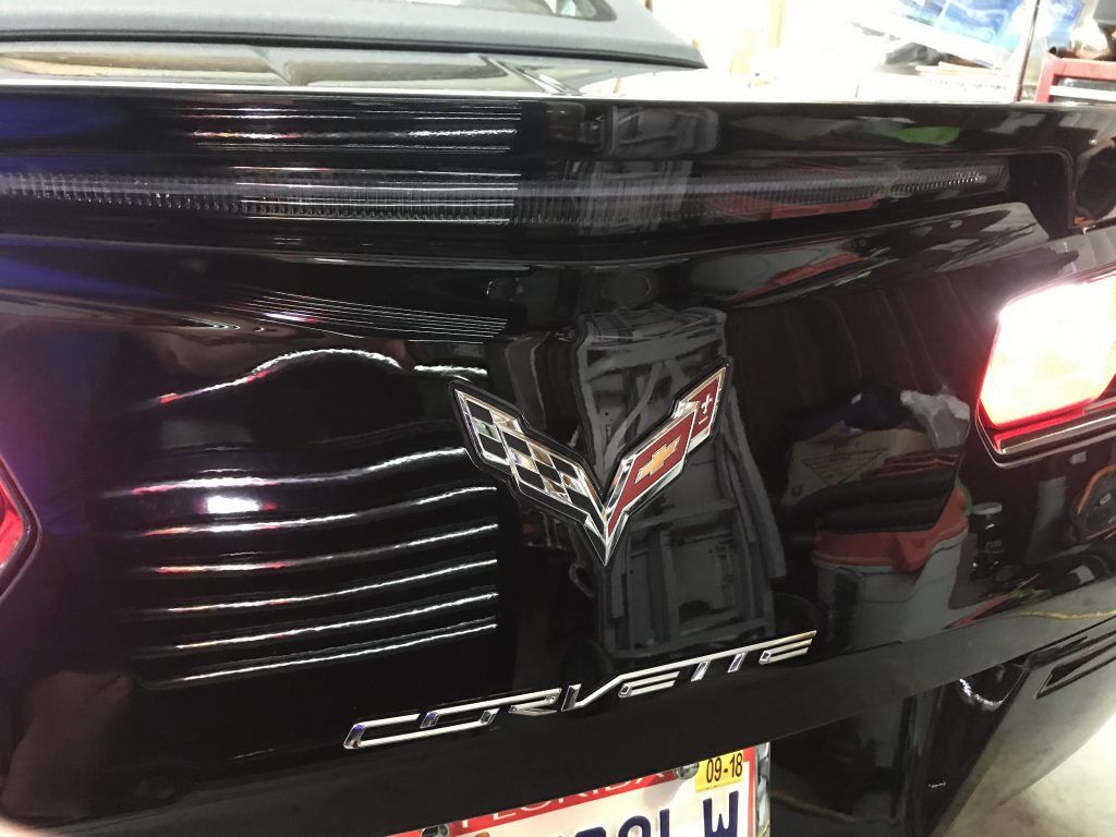 A black corvette is parked in a garage with a license plate.