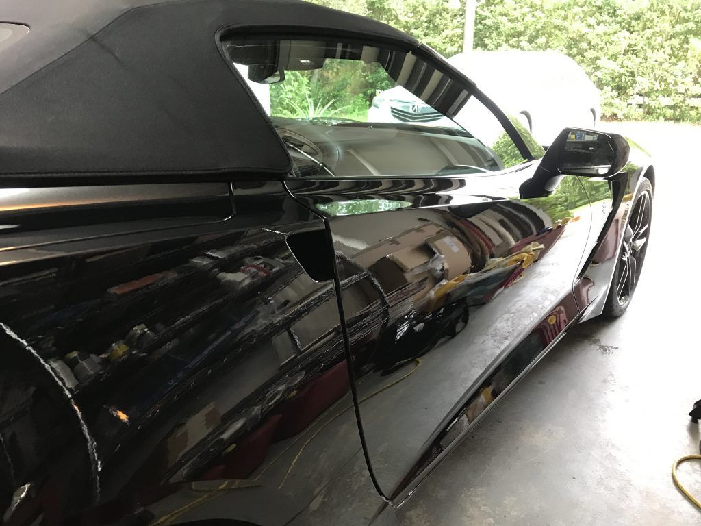 A black convertible sports car is parked in a garage.