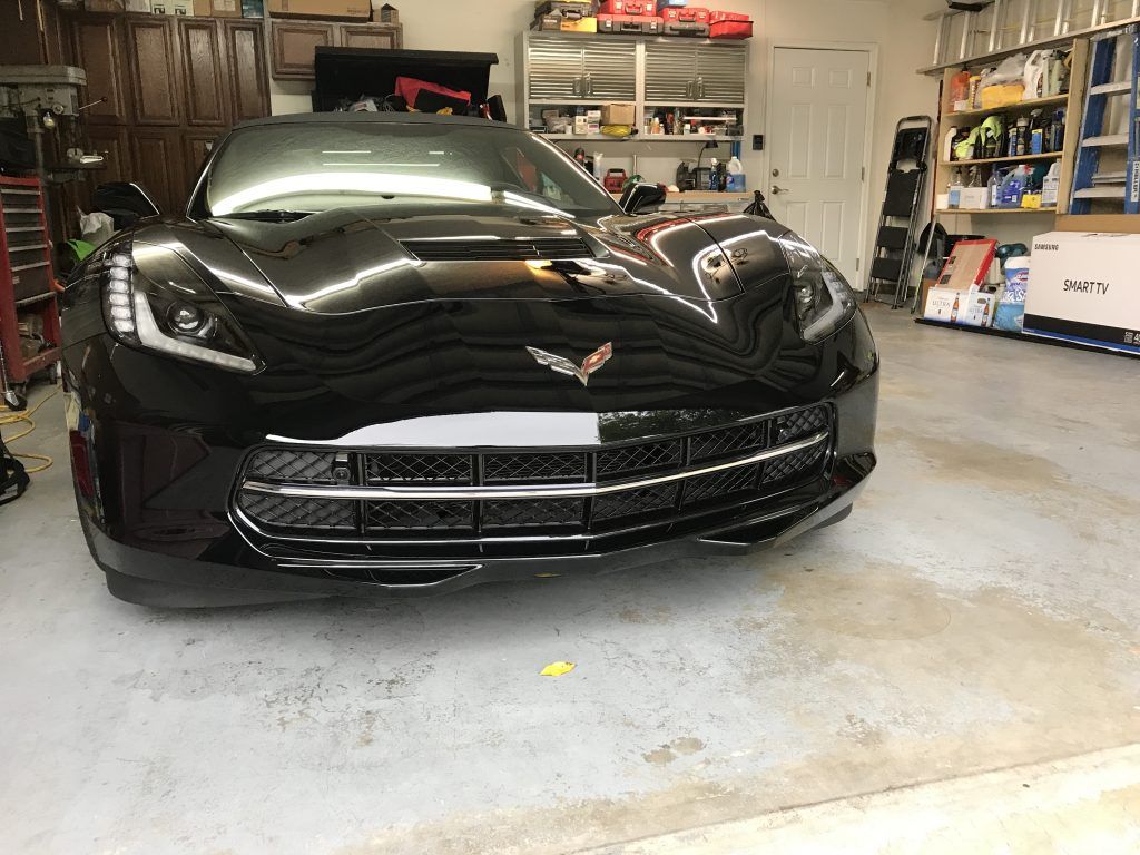 A black sports car is parked in a garage.