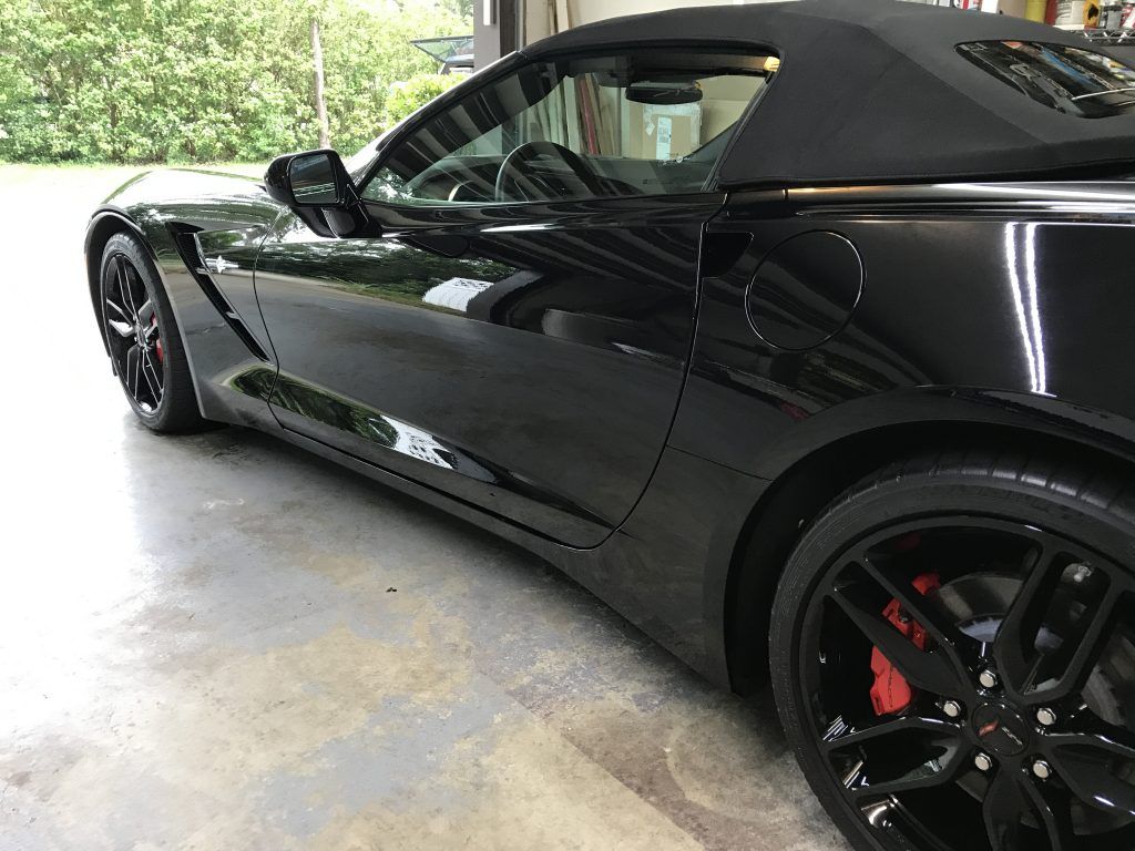 A black convertible sports car is parked in a garage.