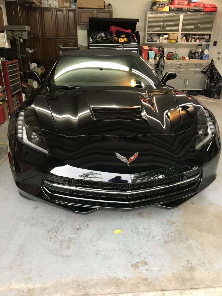 A black corvette is parked in a garage.
