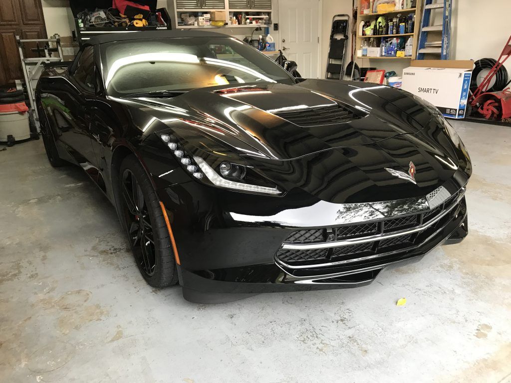 A black sports car is parked in a garage.