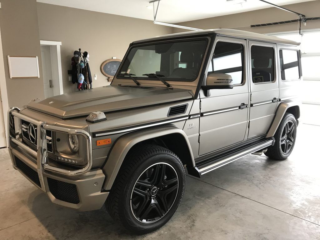 A silver mercedes benz g63 is parked in a garage.