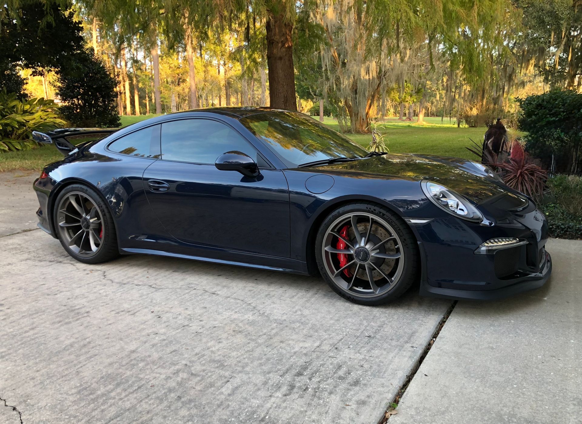 A black porsche 911 gt3 is parked in a driveway.