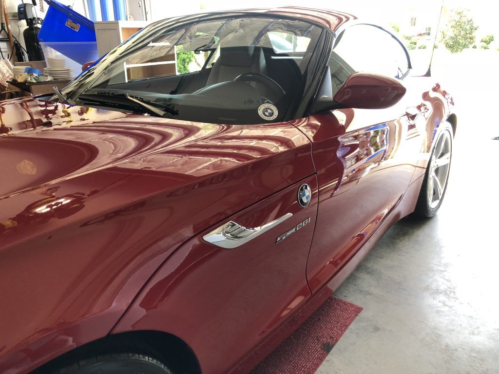 A red bmw z4 is parked in a garage.
