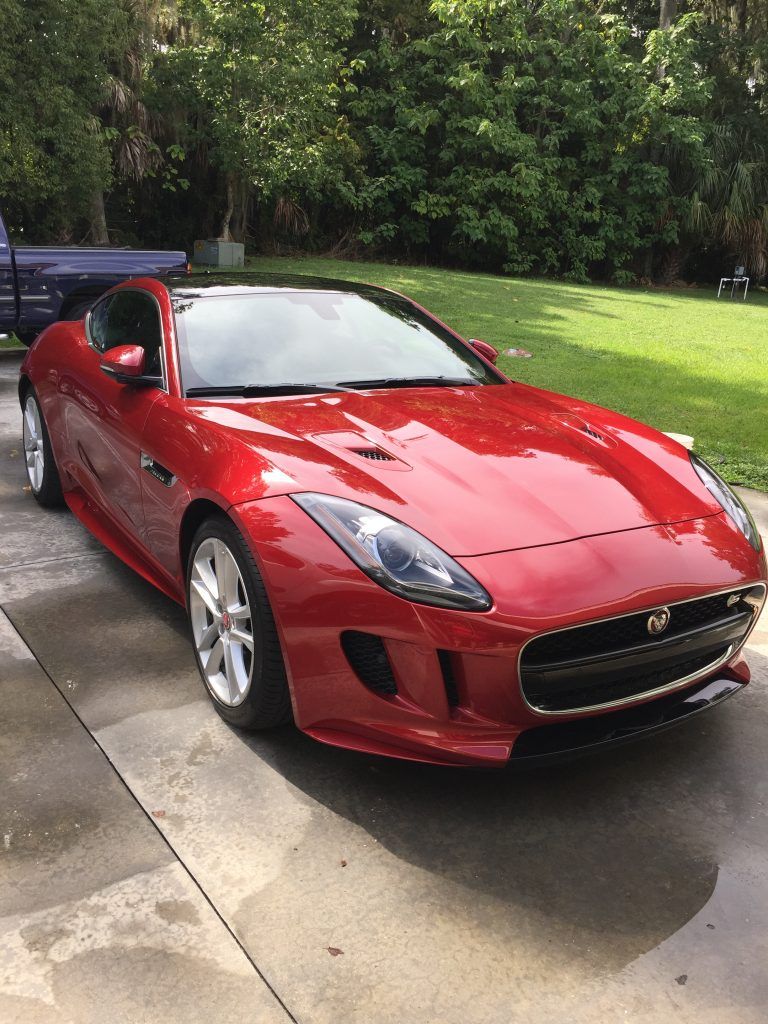 A red sports car is parked in a driveway.