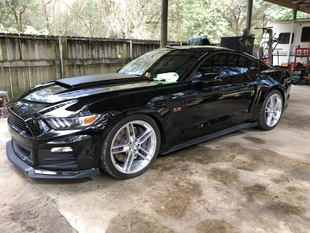 A black ford mustang is parked in a garage.