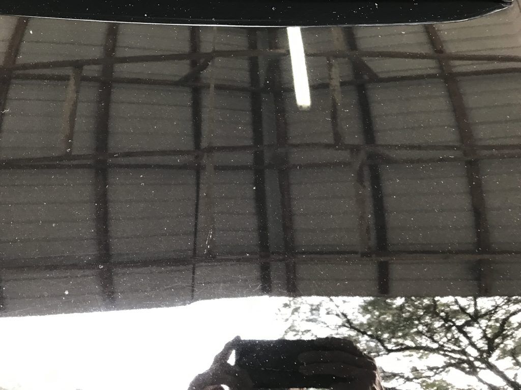 A close up of a car hood with a reflection of a building