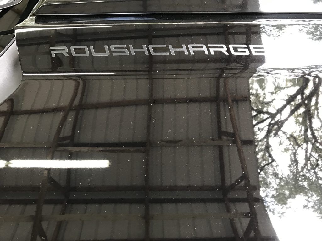 A black car with the word roush charge on the hood