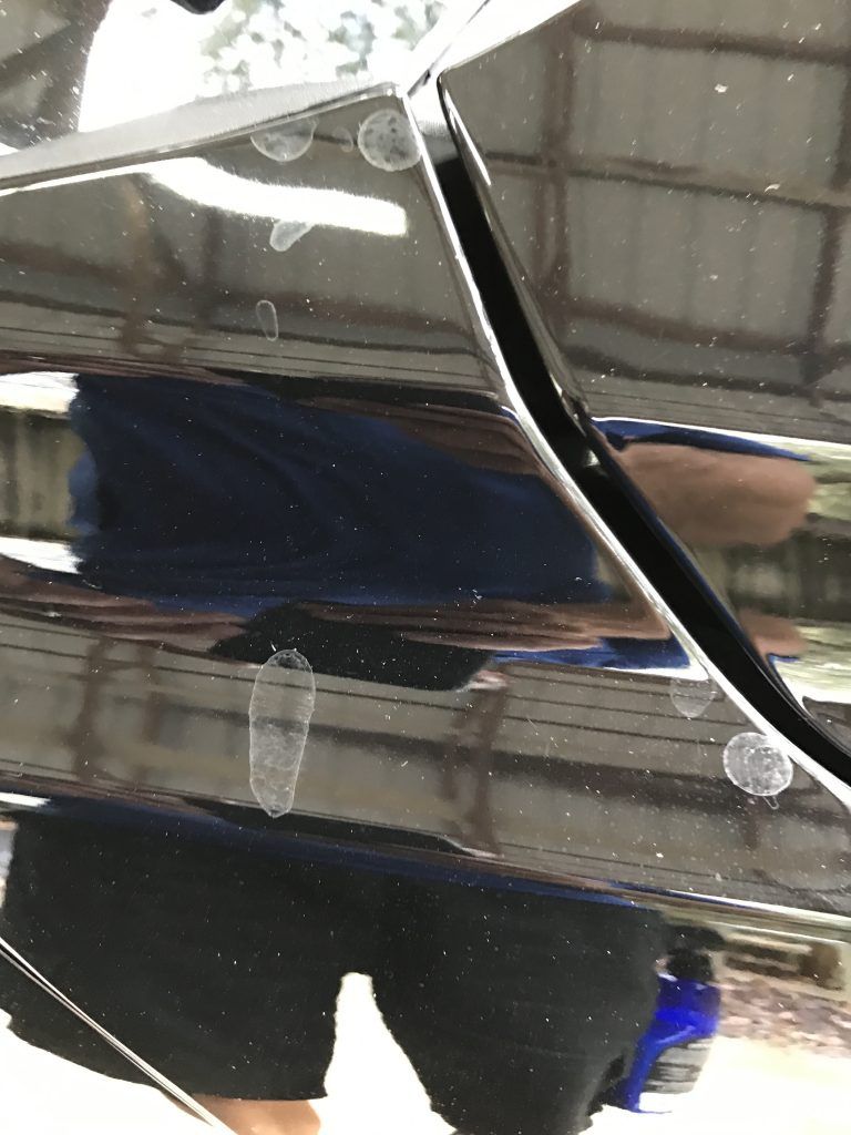 A person is standing in front of a black car.