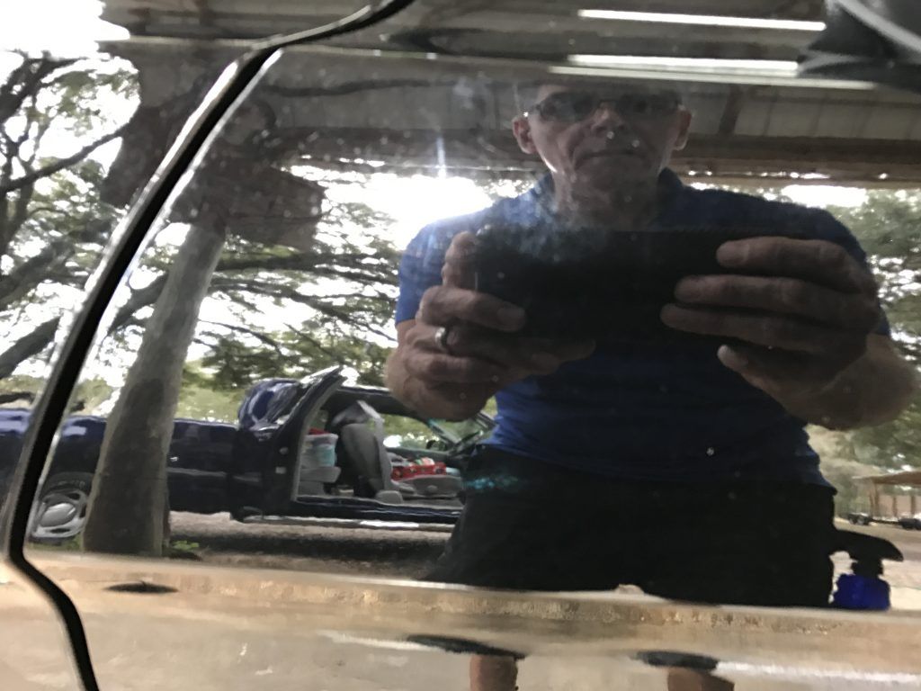 A man is taking a picture of himself in a car window.