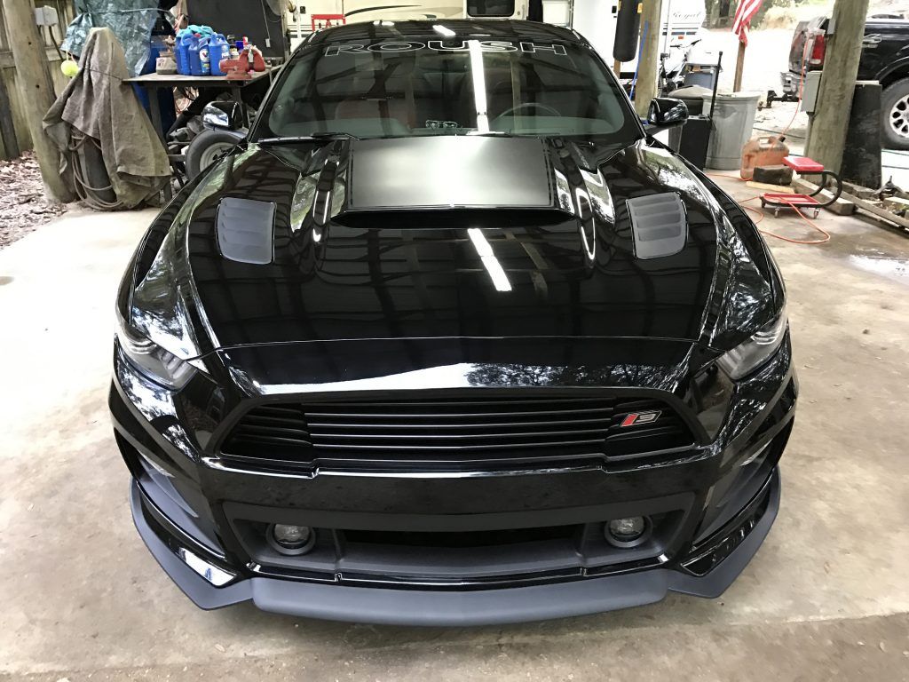 A black ford mustang is parked in a garage.