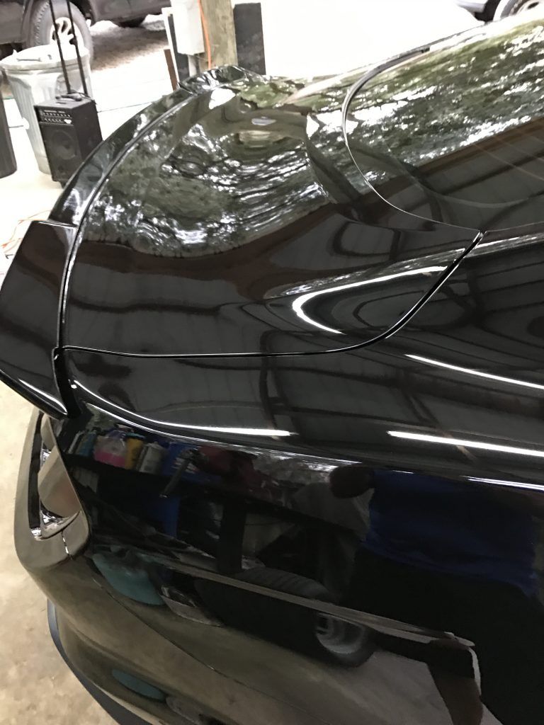 A close up of the hood of a black car in a garage.