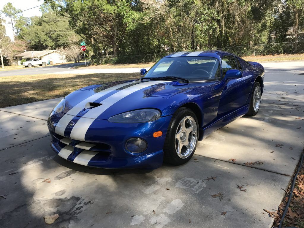 A blue and white dodge viper is parked in a driveway.