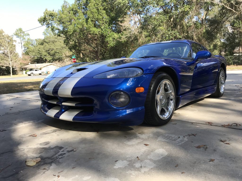 A blue and white dodge viper is parked in a driveway.