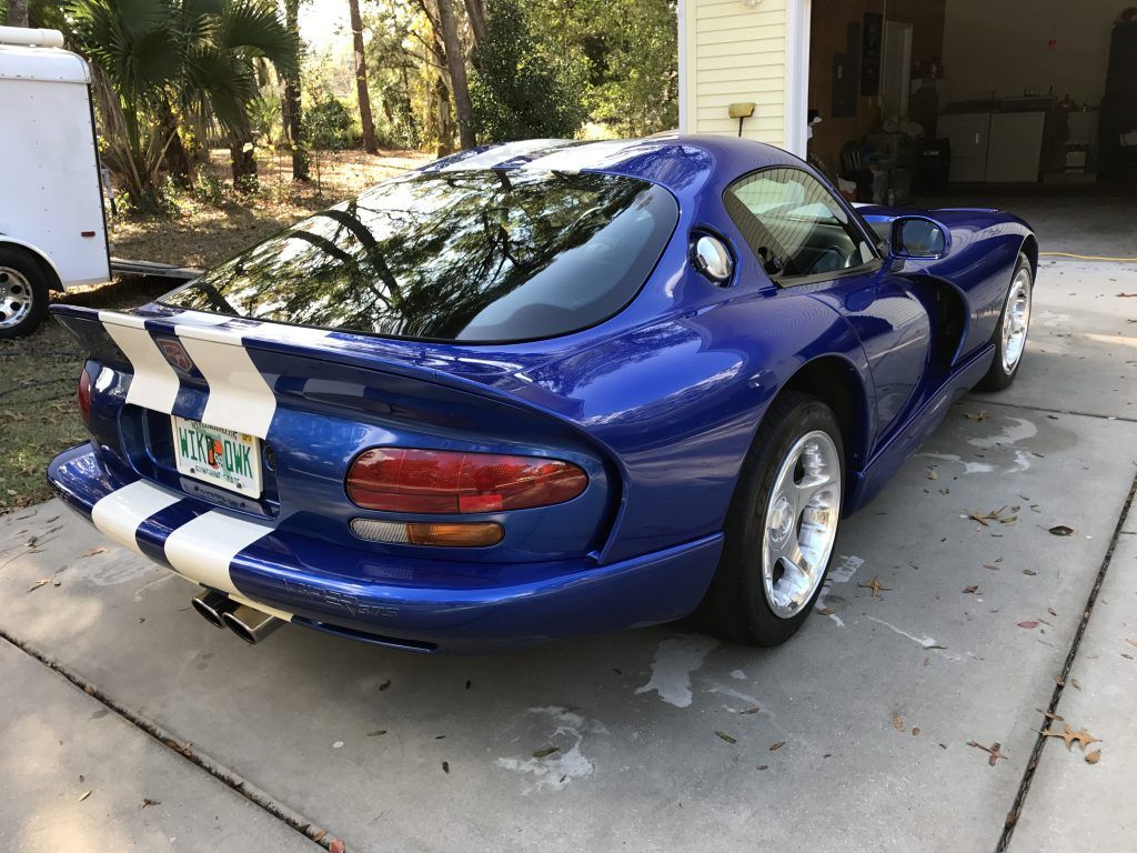 A blue dodge viper is parked in a driveway in front of a garage.