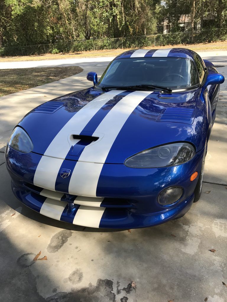 A blue and white dodge viper is parked in a driveway.