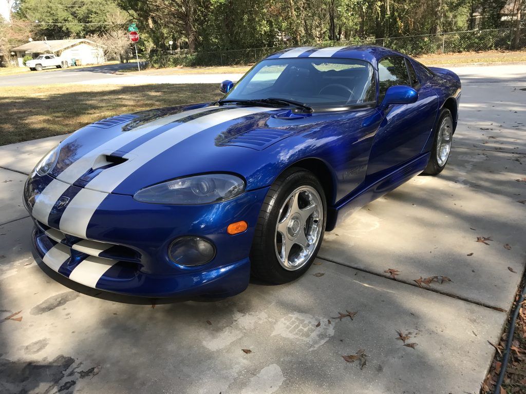 A blue and white dodge viper is parked in a driveway.