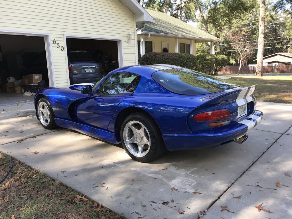 A blue dodge viper is parked in front of a garage.