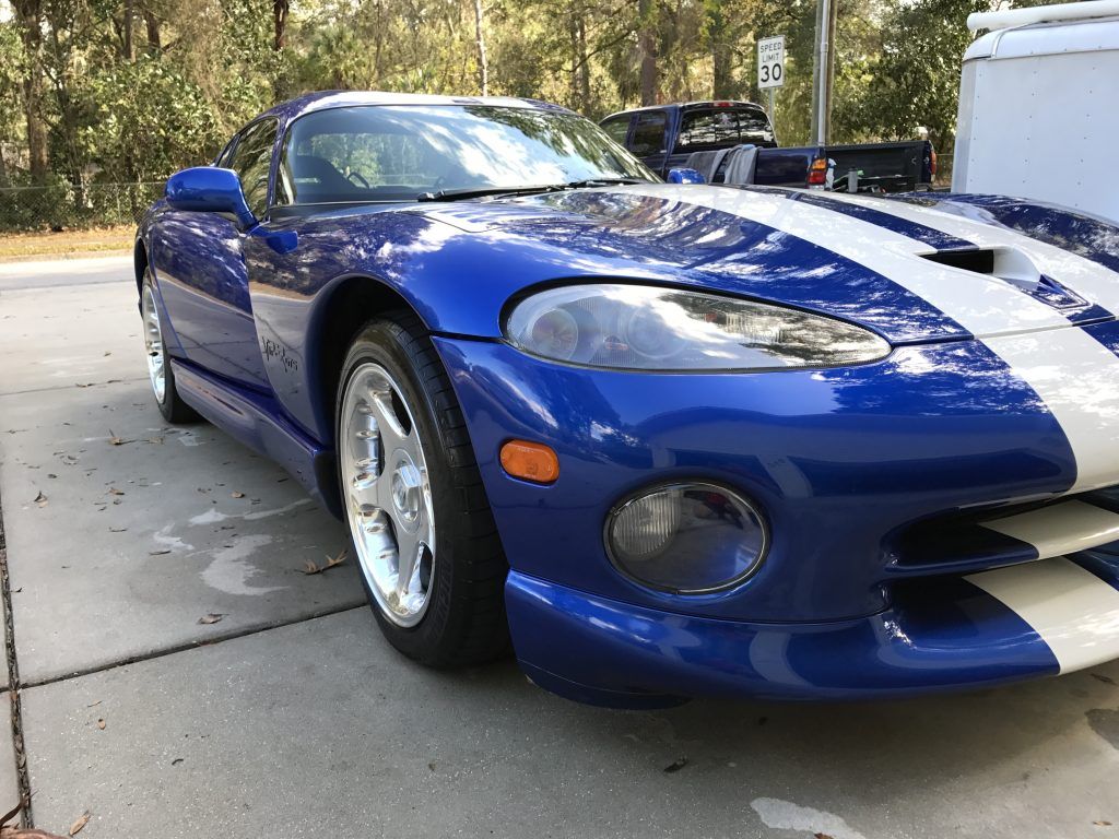A blue and white dodge viper is parked in a driveway.